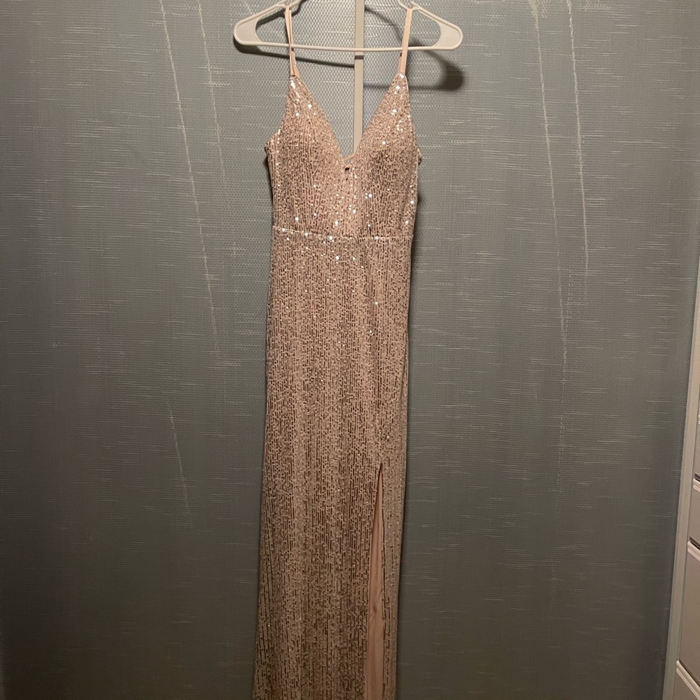 A gold sequin long formal dress with a slit.